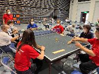 写真：スポーツ推進委員と参加者が卓球バレーをしている様子で、1つの机を囲って板でボールを打ち合っています
