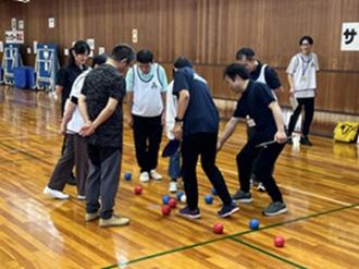 写真：試合後にボールを囲みながらスポーツ推進委員と参加者が得点を確認しています