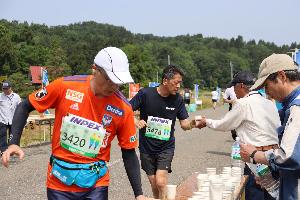 写真：潮風マラソンのボランティアが選手に給水用の水を渡している様子です