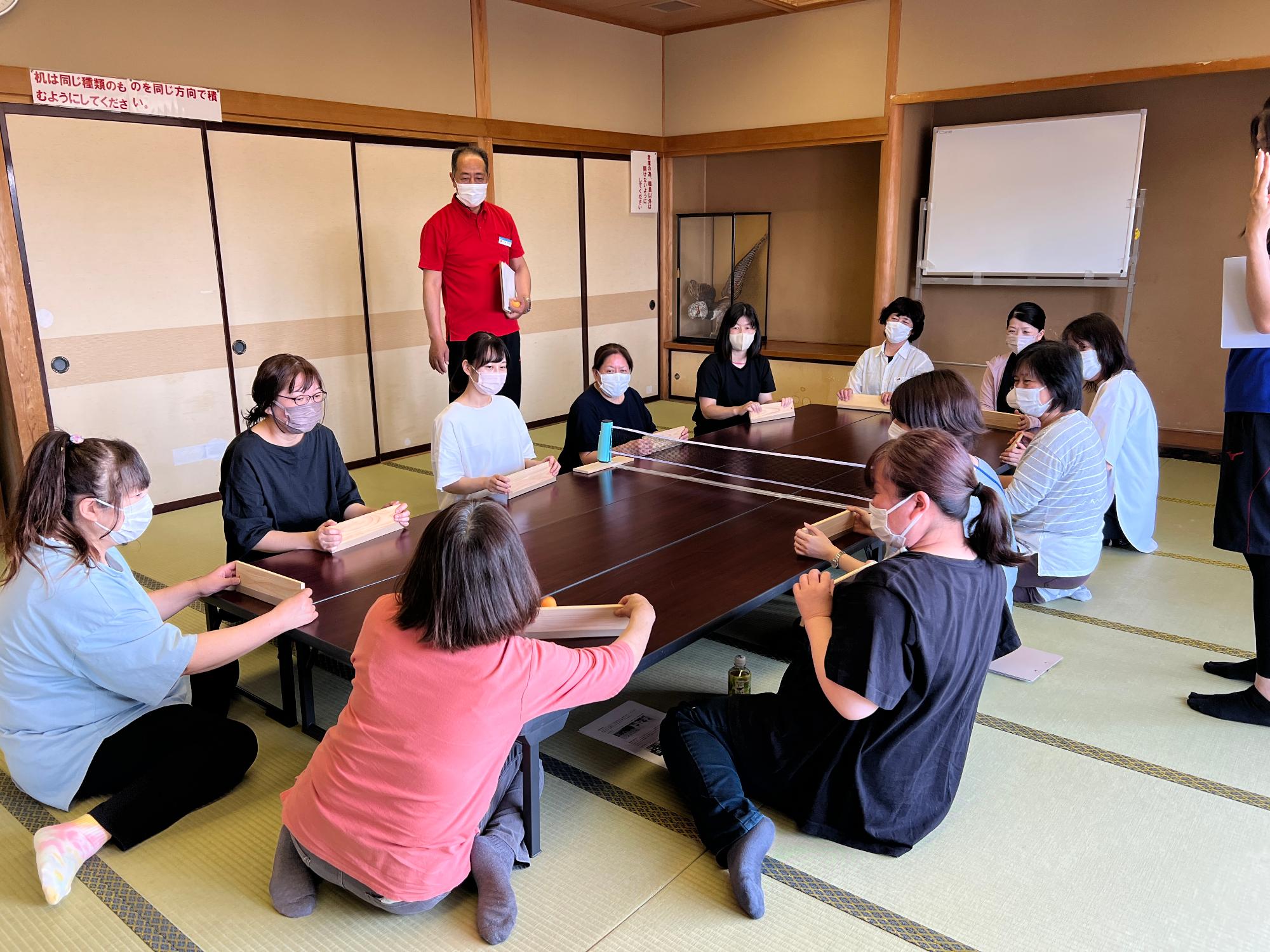 写真：座卓を3つ並べて卓球バレーをする参加者