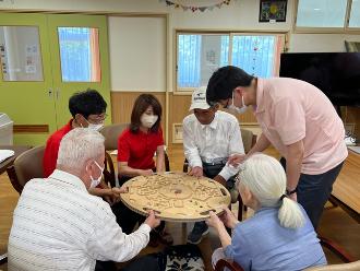 写真：つながロードの様子。スポーツ推進委員と利用者がつながろーどの取っ手を持ち穴に落とさないようにゴールを目指しています