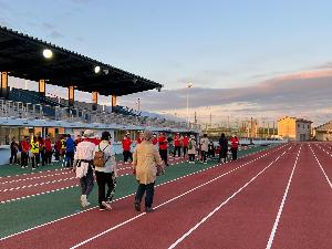 写真：夕暮れの陸上競技場を歩く参加者の様子です