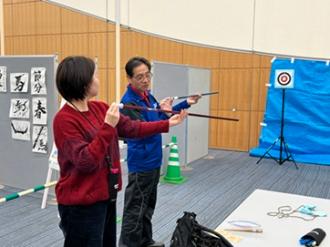 写真：スポーツ推進委員が参加者にスポーツ吹き矢の持ち方を教える様子