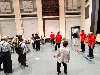 写真：赤いポロシャツを来たスポーツ推進委員がボッチャの説明をしています。参加者が周りで説明を聞いています