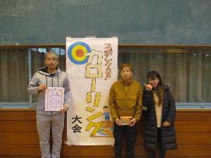 写真：カローリング山ブロックで優勝した柏木町Aの3人が賞状をこちらに向けている記念写真