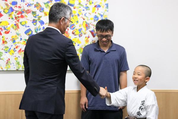 写真：目崎選手と市長が笑顔で握手しています