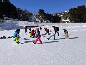 写真：スノーボードスクールの参加者が円になって準備体操をしています
