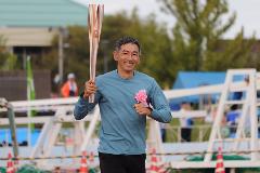 写真：聖火リレーの第一走者為末大さんがにこやかに聖火を持って走っています