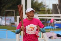 写真：第四走者の現役マスターズ陸上の選手黒崎さん。今回の市民大運動会のピンクのTシャツを着ています