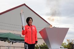 写真：最後のランナーの小出みくさん。聖火台に火を点け炎が燃え上がっています