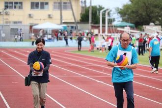 写真：ボール運びリレーの参加者がラケットに水球ボールを乗せて慎重に運んでいます