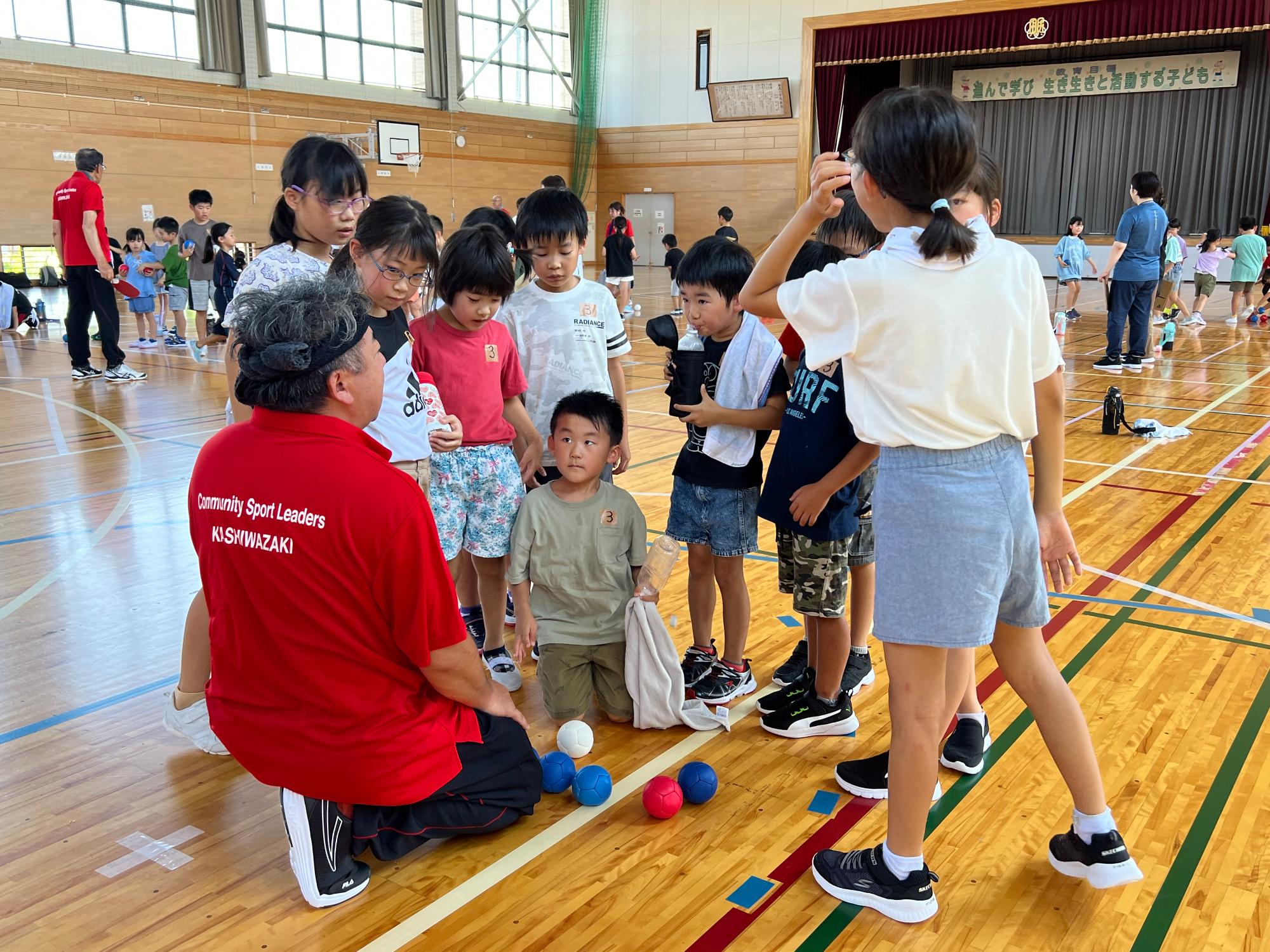 写真：スポーツ推進委員の周りに集まって得点の集計を見守る子どもたち