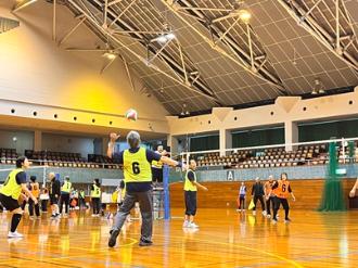 写真：参加者がボールを相手のコートに打ち返そうとしています。同じチームの人がそれを眺めています