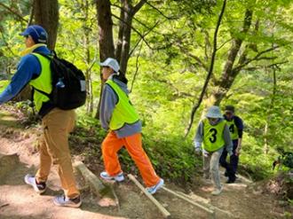 写真：黄色のビブスを着用した参加者が傾斜のある登山道を登っている様子