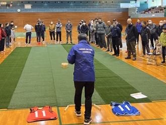 写真：スポーツ推進委員1人がコートに立ち、ルールを説明しています。コートの周りを参加者が囲んでいます