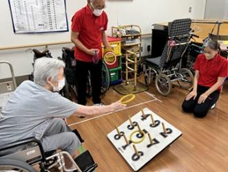 写真：車いすに乗ったまま輪投げを楽しむ高齢者