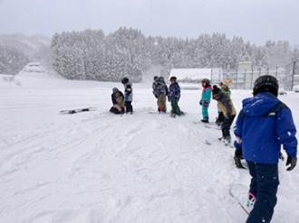 写真：内山さんが参加者に滑り方を教えている様子。その後ろに参加者が列になっています