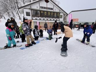 写真：内山さんが参加者に滑る時の姿勢を教えています。参加者が真剣に話を聞いています