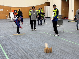 写真：男性の投げたモルックがうまくスキットルに当たっています