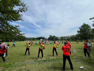 写真：スポーツ推進委員がラジオ体操の模範になり参加者とラジオ体操をしています。スポーツ推進委員は赤いポロシャツを着ています