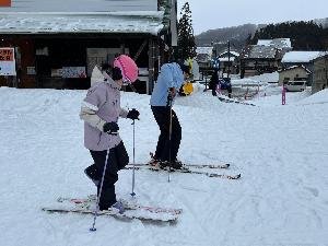 写真：指導者と参加者の小学生がスキーを履く練習をしている様子です