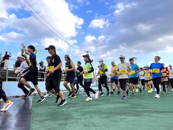 写真：参加者がスタートし、陸上競技場からコースに出ていく様子
