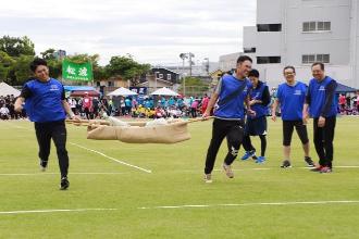 写真：防災レスキューリレーで、担架に乗せた数個の土のうを男性2人が急いで運んでいます