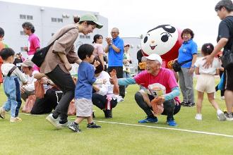 写真：大会名誉顧問の黒崎ひろあきさんが幼児レースの参加賞を子どもに手渡しています