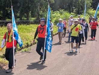 写真：野外でスポーツ推進委員が、参加者の前を先導しながらでウォーキングをしている写真