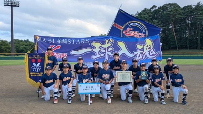 写真：柏崎スターズの集合写真。柏崎スターズと書かれたプラカードや優勝旗、賞状、楯を持っています