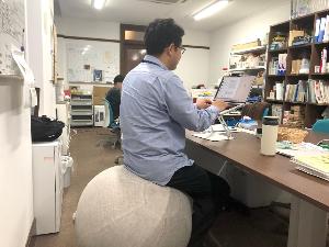 写真：男性職員がバランスボールに座りながらパソコンを操作しています
