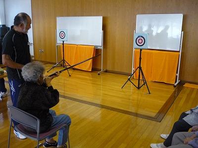 スポーツ推進委員が高齢者にスポーツ吹矢を教えている写真