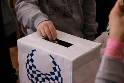 投票箱があり、人が投票箱に手を入れている写真