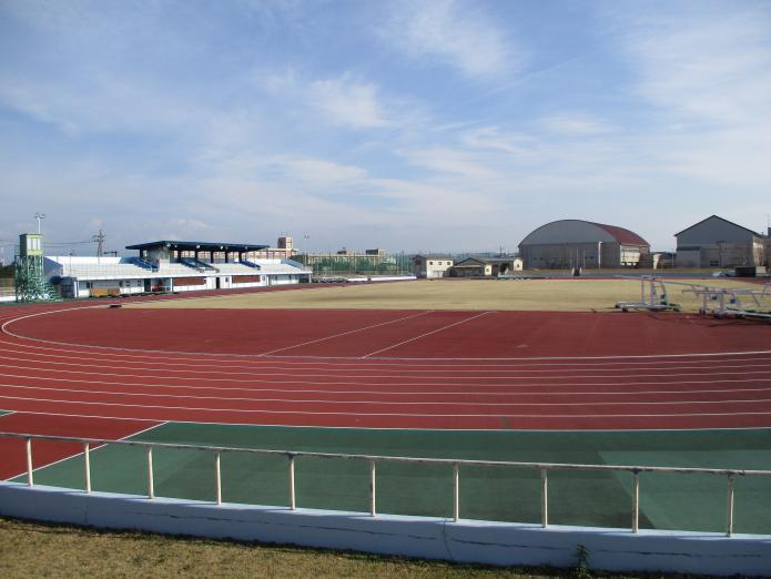 陸上競技場の赤茶色のトラックレーンと奥にはメインスタンドがある「柏崎市陸上競技場」の内部の写真