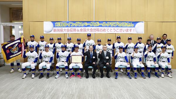 写真：西巻副市長と近藤教育長を囲んで記念撮影。全員がガッツポーズをしています