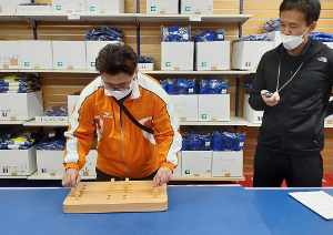 写真：男性がペグボードと呼ばれる木製の用具を使用して、手作業の測定をしています