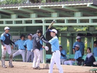 写真：水色のユニフォームを着た選手が複数人います。手前にバットをかまえる選手も写っています