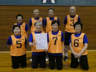 写真：優勝したひすみチームの記念写真の様子。オレンジ色のビブスを着用し、皆さんにこやかな表情です