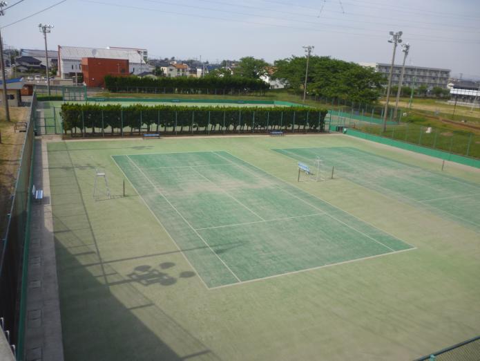 フェンスに囲まれたテニスコートが2面ある写真