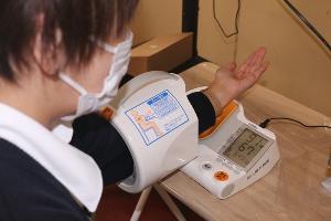 写真：女性従業員が血圧を測っています