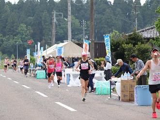 写真：新道給水所の様子。ボランティアが給水用の水を用意し、ランナーが受け取り給水しています