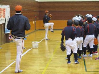 投球姿勢になる小野投手とそれを見ている小学生たちの写真