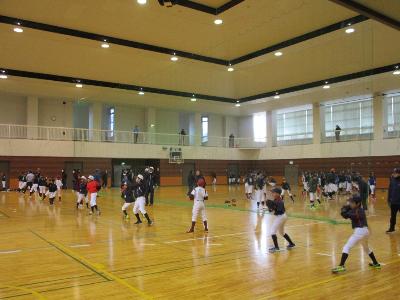西山総合体育館のメインアリーナでキャッチボールをするたくさんの小学生の写真