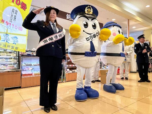 写真：ウオロク店内での広報の様子。新潟県警のマスコットキャラクターと並んで敬礼をしています