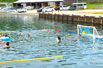 写真：浮き輪を使って泳ぎながらゴールに向かってシュートする子ども