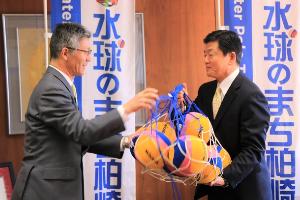 写真：市長が堀井会長に水球ボールを贈呈しています