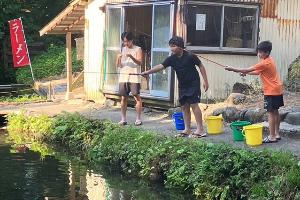 写真：餌をつけて、釣り竿を釣り堀に垂らしています