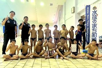 写真：ブルボンKZ小学生と指導者の集合写真。人差し指を立てて優勝の喜びを表しています