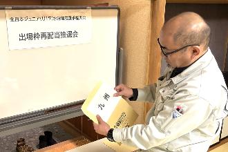 写真：大会実行委員が1つ目の封筒を選び、九州ブロックを引きました