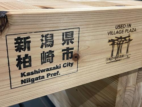 写真：「新潟県柏崎市」の文字と「USED IN VILLAGE PLAZA」と選手村で使用されたことを示す焼き印。どのベンチにも入っています。
